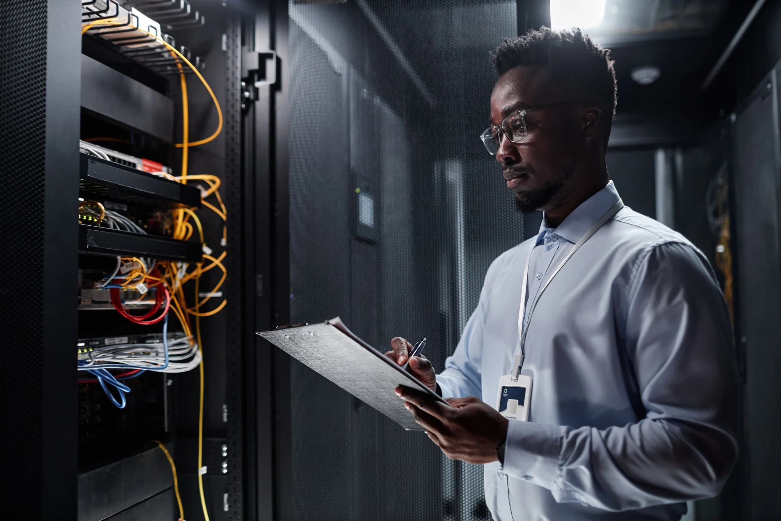 Black network engineer configuring switches in a server rack